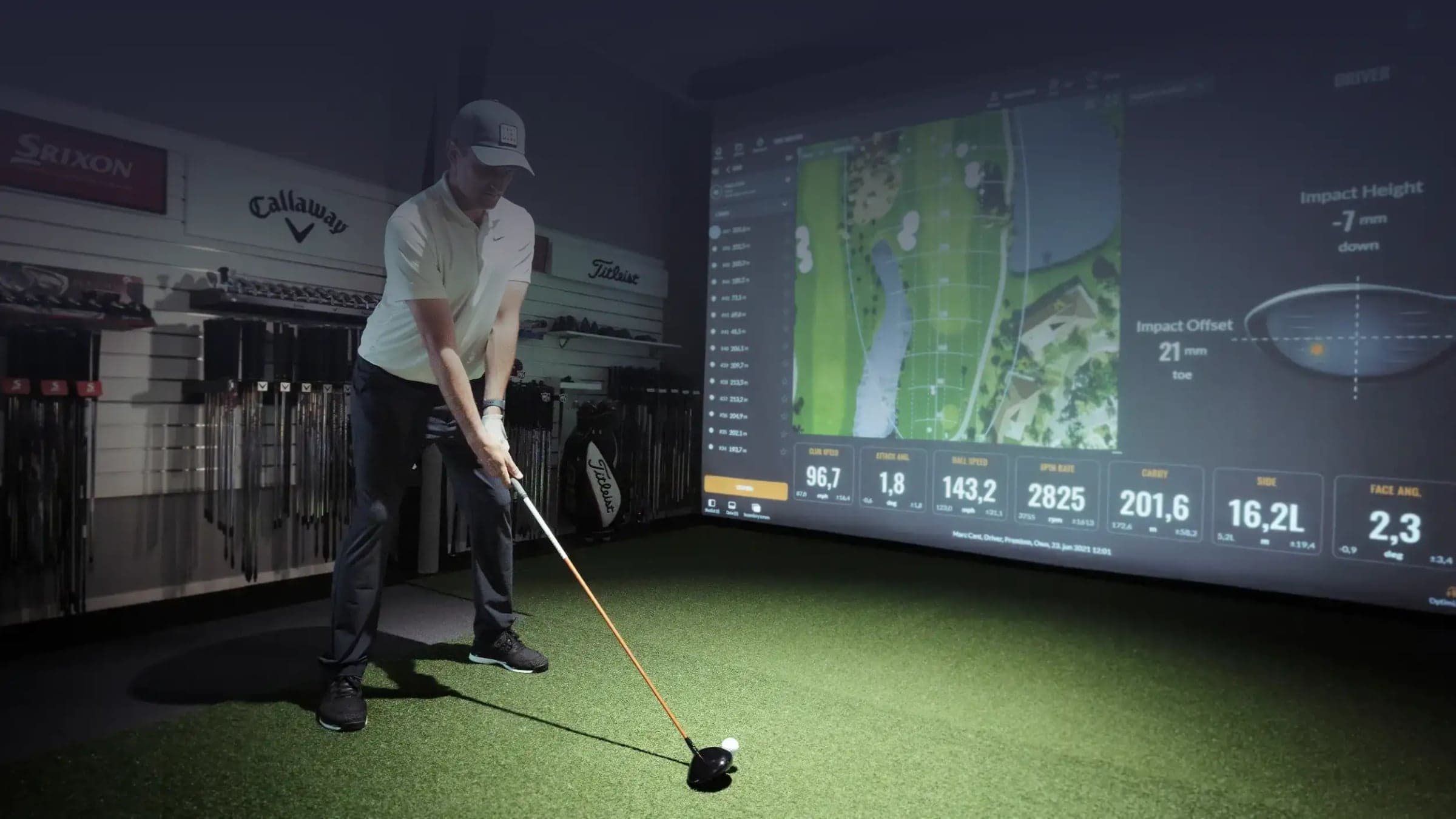 Swing Loose Indoor Golf — Golfer at impact in a bay, ball-flight data panel on the screen, a wall of Callaway/Titlei